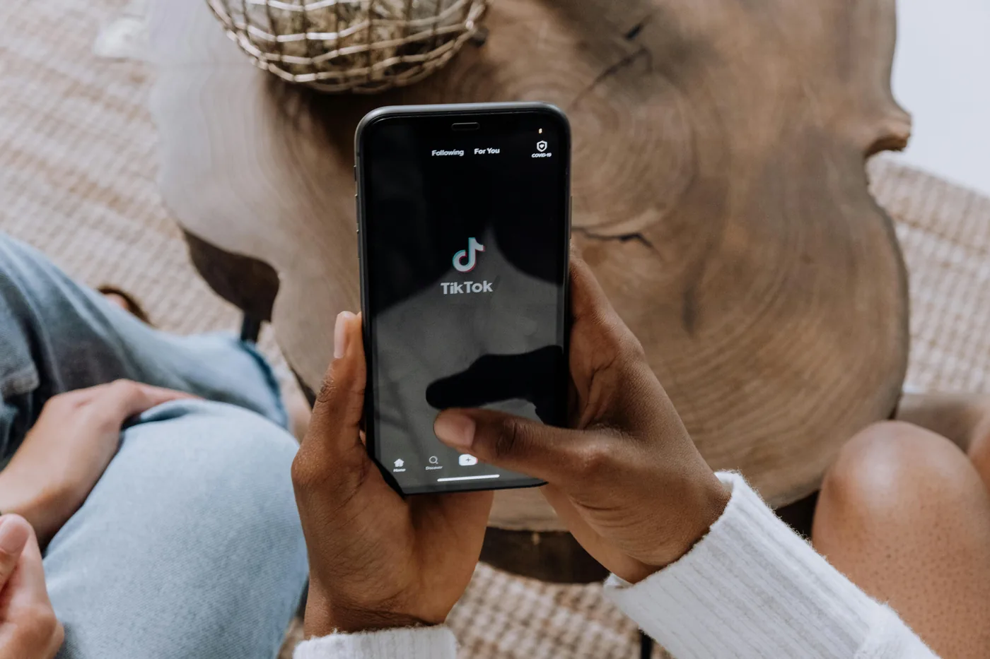 Hands holding a phone with the TikTok app open